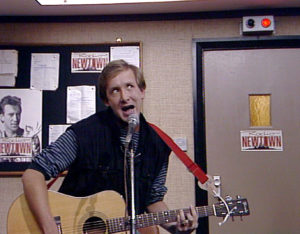 A young man enthusiastically playing his guitar on the radio