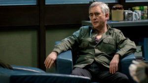 Steve, shirt mostly unbuttoned, sitting casually in an armchair in the office